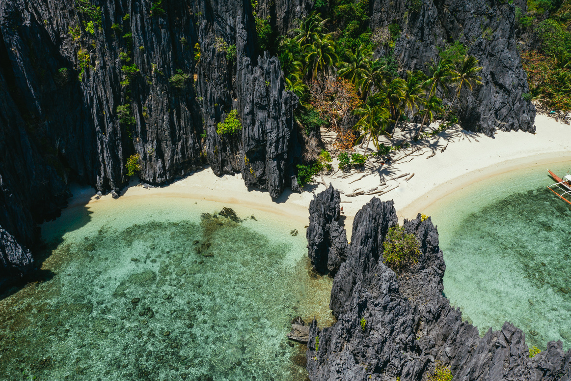 Small lagoon in El nido. People walking on the white sand, with