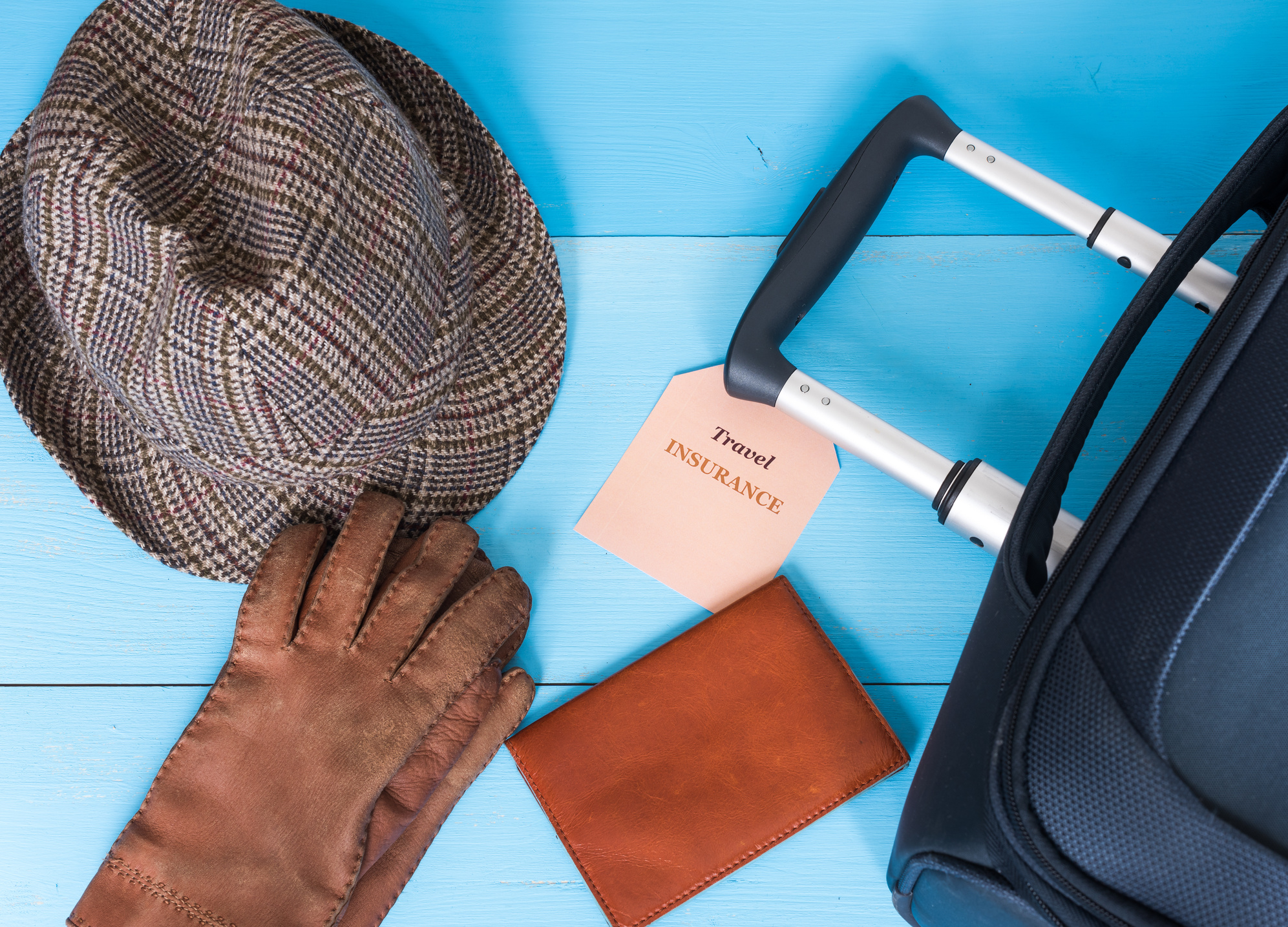 Travel insurance concept. Suitcase, hat, gloves, passport case, insurance tag.